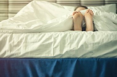 Gün batımında battaniyenin altında kadın bacakları. 