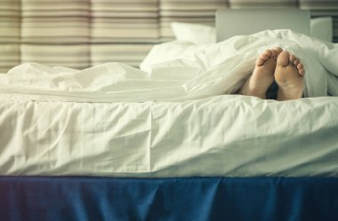 Kadın bacaklarını batımında battaniye altında. Görüntü'nün içinde laptop ile erkek