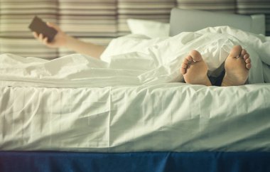 Kadın bacaklarını batımında battaniye altında. Görüntü'nün içinde laptop ile erkek