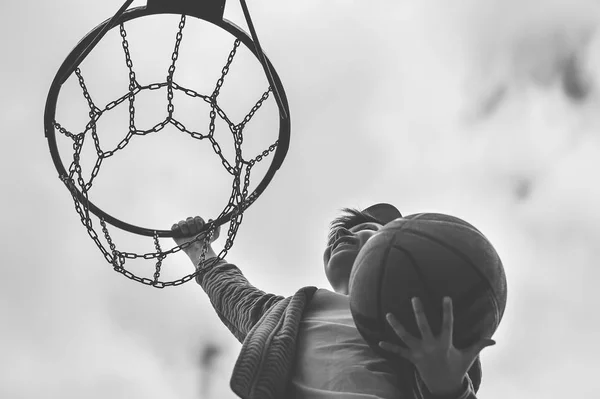 En liten pojke hoppar och gör mål spelar streetball, basket. Kastar en basket boll i ringen. Begreppet idrott — Stockfoto