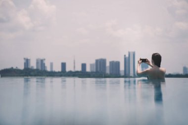 Malezya Putrajaya şehir arka plan üstünde hareket eden telefon ile havuz güzel kız. Putrajaya gökdelenler