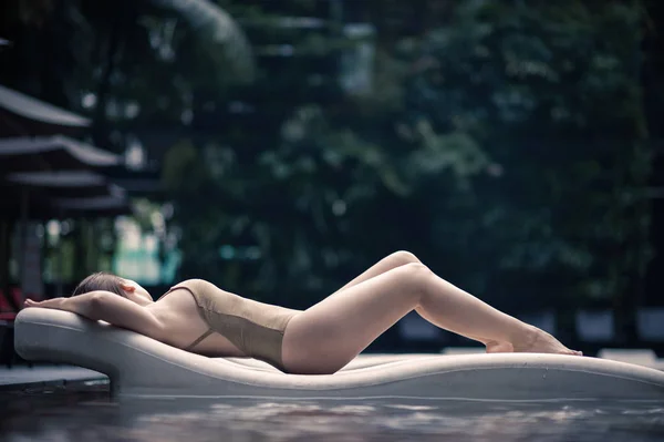 Piękna samotna dziewczyna leży na leżaku w strój kąpielowy w basenie w tropikach Malezji. Kobieta w wody w basenie — Zdjęcie stockowe