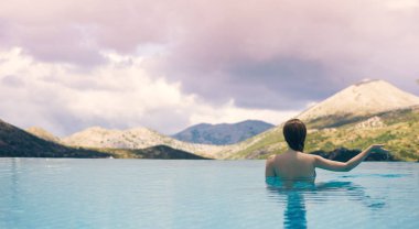 Manzara Dağları'nın ve Güney Tirol bulutlar günbatımı üzerinde arka planda çatıdaki havuzda genç erkek