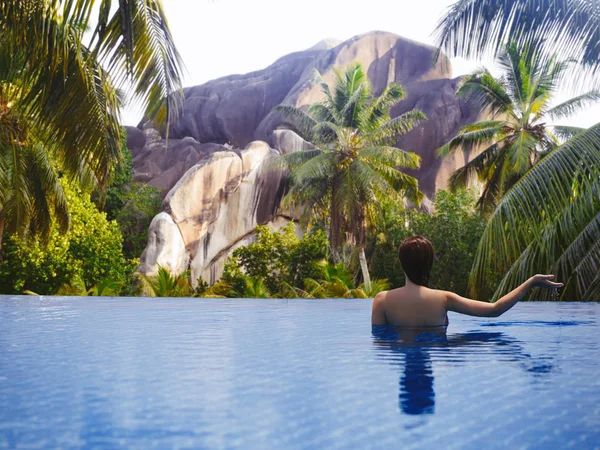 Young female in the pool on the roof on the background of Seychelles island of La Digue