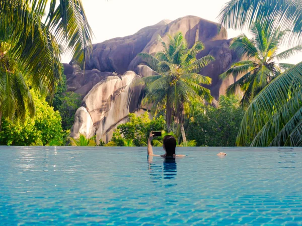 Young female in the pool on the roof on the background of Seychelles island of La Digue