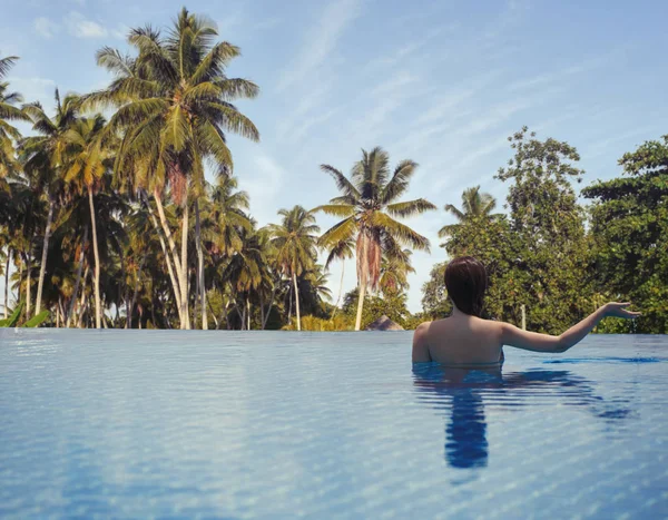 Young female in the pool on the roof on the background of Seychelles island of La Digue