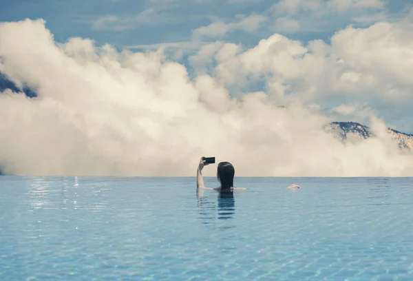 Jovem fêmea na piscina no telhado no fundo da Paisagem das Montanhas e nuvens do Tirol do Sul no pôr do sol — Fotografia de Stock