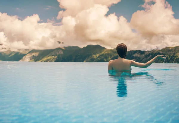 Junges Weibchen im Pool auf dem Dach vor dem Hintergrund der Berg- und Wolkenlandschaft Südtirols bei Sonnenuntergang — Stockfoto