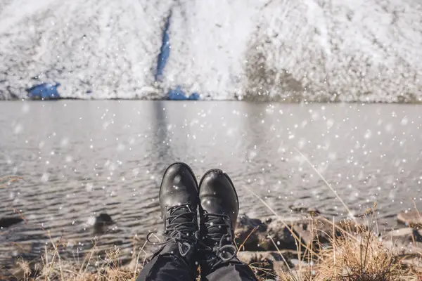 Pernas femininas em botas de caminhada pretas no fundo das montanhas de neve na Suíça. Neve nos sapatos femininos — Fotografia de Stock