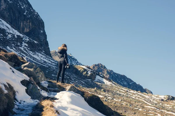 Uma fotógrafa com câmera em uma jaqueta de inverno com pêlo na montanha de neve na Suíça. Fluela passa na Suíça no inverno — Fotografia de Stock