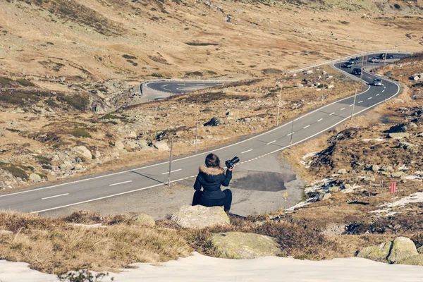 Uma fotógrafa com câmera em uma jaqueta de inverno com pêlo na montanha de neve na Suíça. Fluela passa na Suíça no inverno — Fotografia de Stock