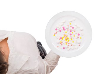 Üzerinde ilaç hapları ya da kapsüller olan beyaz bir bluz giyen bir garsonun üst görüntüsü. Beyaz arka plan. Sağlıksız ve antibiyotik gıda kavramı. İzole edilmiş