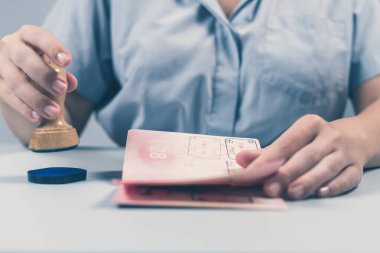 Havaalanında göçmenlik ve pasaport kontrolü. Kadın sınır kontrol memuru pasaportuna mühür basıyor. Kavram