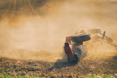 Farmer tractor with disc harrow system working on a stubble field  