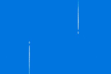 Uçaklar açık mavi gökyüzünde izler bırakır. Birçok uçağın yolculuk konseptinden aşağıdaki izlere bak