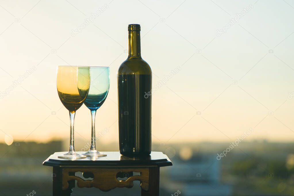 A bottle of wine and two glasses on a sunset background