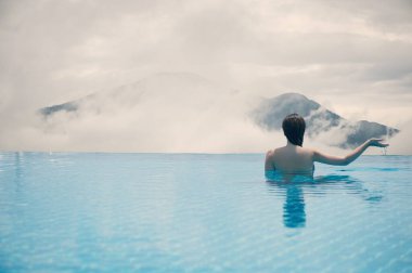 Çatıdaki havuzda genç bir bayan İtalyan dağının arka planında ve Güney Tyrol 'da bulutlar. Gölün ve dağın karşısındaki çatıdaki havuzda bir kadın.