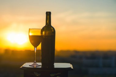 Gün batımında bir şişe şarap ve iki bardak.