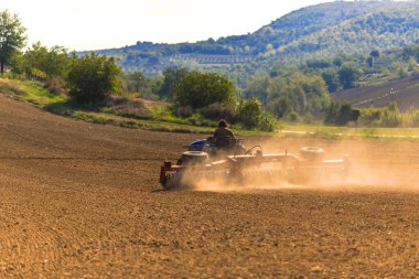 Farmer tractor with disc harrow system working on a stubble field  