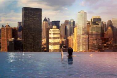  New York City, Manhattan 'daki gökdelenlerin arka planındaki havuzda genç bir kadın.