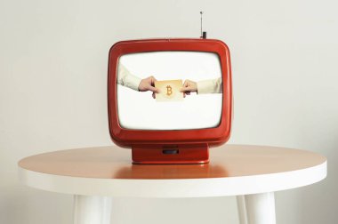 Eski bir TV ekranındaki kadın ve erkeklerin elinde kripto para birimleri var. Yaratıcı bir kavram. Geleceğe bakmak