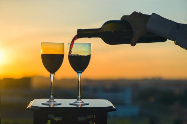 Gün batımında bir şişe şarap ve iki bardak.