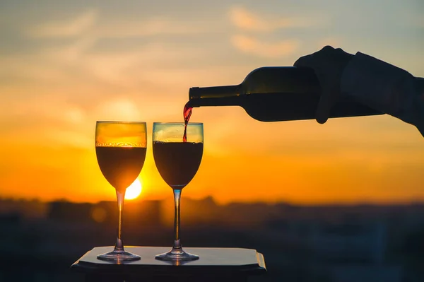 Mão Feminina Com Garrafa Derrama Vinho Tinto Copos Fundo Pôr — Fotografia de Stock