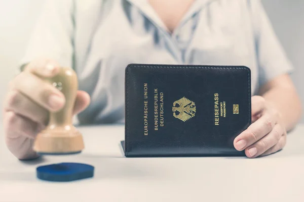 Immigration and passport control at the airport. woman border control officer puts a stamp in the Deutsch passport of German citizen. Concept