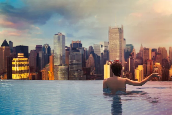 マンハッタンの高層ビルの背景にある屋根の上のプールの若い女性 — ストック写真