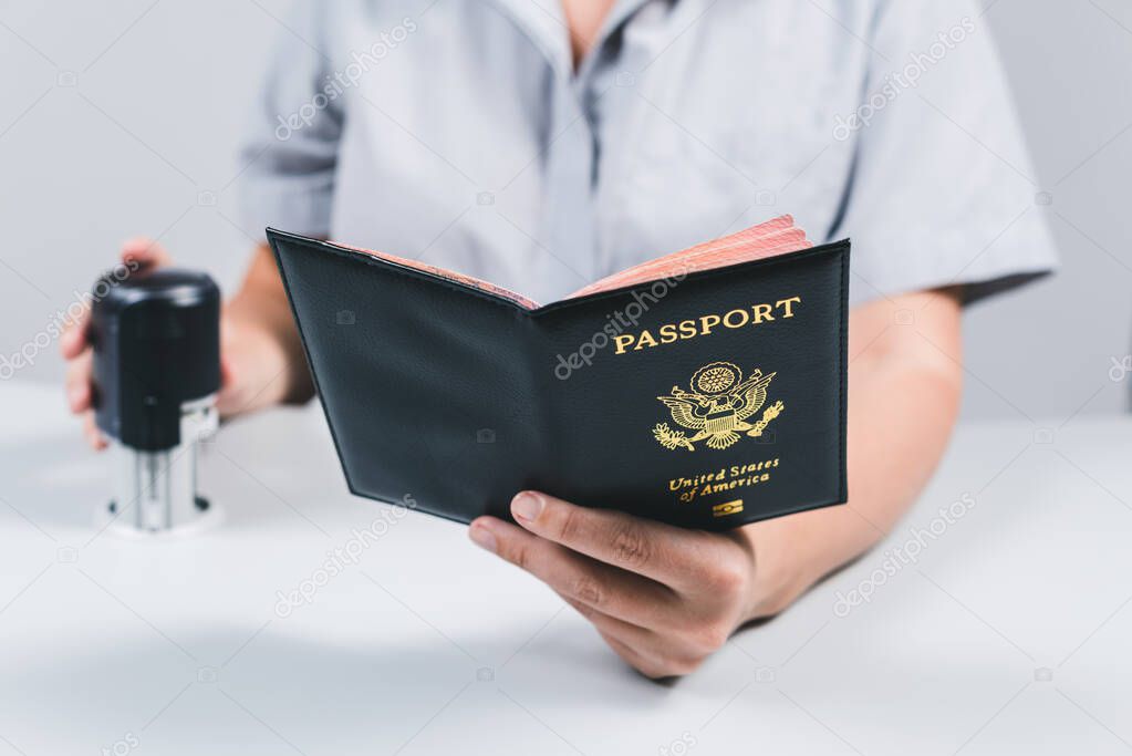 Immigration and passport control at the airport. woman border control officer puts a stamp in the US passport of american citizen. Concept