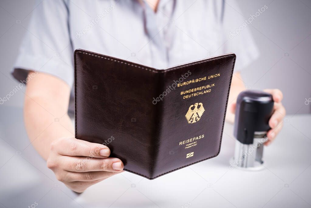 Immigration and passport control at the airport. woman border control officer puts a stamp in the Deutsch passport of German citizen. Concept