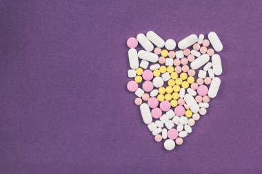 Beyaz arka planda renkli haplardan yapılmış kalp şekli. Kavram
