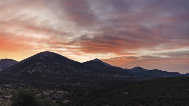 Yunanistan 'ın Kefalonia adasındaki dağdaki yel değirmenlerinin gün batımı manzarası.