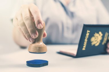 Havaalanında göçmenlik ve pasaport kontrolü. Kadın sınır kontrol memuru Amerikan vatandaşının pasaportuna mühür basıyor. Kavram