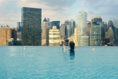  New York City, Manhattan 'daki gökdelenlerin arka planındaki havuzda genç bir kadın.