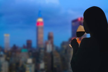 Chicago 'nun arka planında, Illinois, Usa' da bir bardak şarap içen bir kadın. Restoranın çatısında servis var.