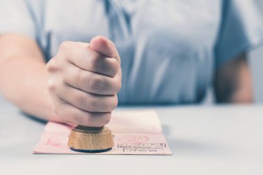 Havaalanında göçmenlik ve pasaport kontrolü. Kadın sınır kontrol memuru pasaportuna mühür basıyor. Kavram
