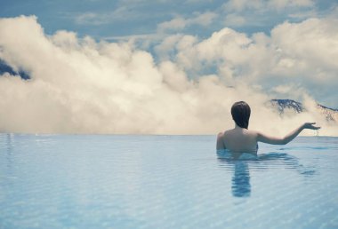 Genç erkek arka planda çatıdaki havuzda manzara Dağları'nın ve Güney Tirol bulutları