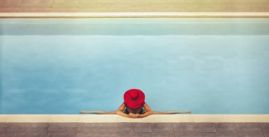 Günbatımında bir sicim havuzda şapkalı bir genç kadın oturur