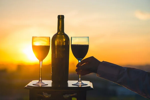 female hand with wine glass on sunset background.