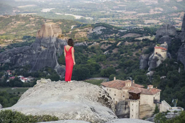 Egy Vörös Ruhás Magányos Lány Szikla Szélén Nézi Meteora Kolostorait — Stock Fotó