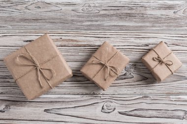 Kaba ahşap arka planda el yapımı kağıt, noel ipi ve ağaçtan hediyeler. Diy..
