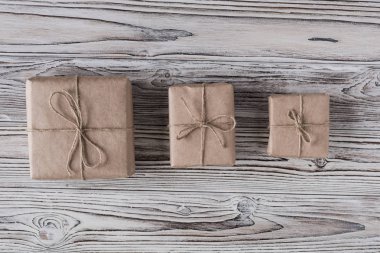 Kaba ahşap arka planda el yapımı kağıt, noel ipi ve ağaçtan hediyeler. Diy..