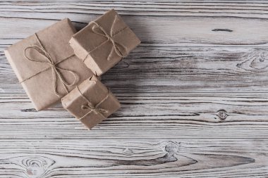 Kaba ahşap arka planda el yapımı kağıt, noel ipi ve ağaçtan hediyeler. Diy..