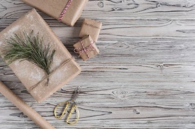 Kaba ahşap arka planda el yapımı kağıt, noel ipi ve ağaçtan hediyeler. Diy..