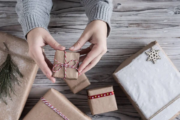 女性包装小礼物 纸板箱在工艺纸 圣诞绳和树在乡村木板的背景 — 图库照片