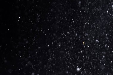 Geceleri kar yağıyor. Siyah arka planda Bokeh ışıkları, havada uçan kar taneleri. Dokuları üst üste koy. Kar fırtınası