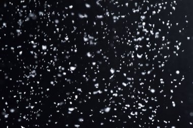 Geceleri kar yağıyor. Siyah arka planda Bokeh ışıkları, havada uçan kar taneleri. Dokuları üst üste koy. Kar fırtınası