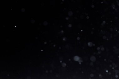 Geceleri kar yağıyor. Siyah arka planda Bokeh ışıkları, havada uçan kar taneleri. Dokuları üst üste koy. Kar fırtınası