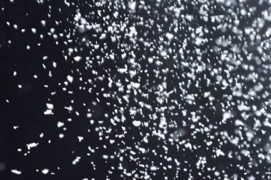 Geceleri kar yağıyor. Siyah arka planda Bokeh ışıkları, havada uçan kar taneleri. Dokuları üst üste koy. Kar fırtınası